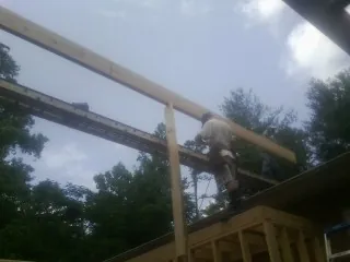 Carpenter setting a ridge beam over a new addition frame — Ice Dam Removal by Roofing Brothers in Powers
