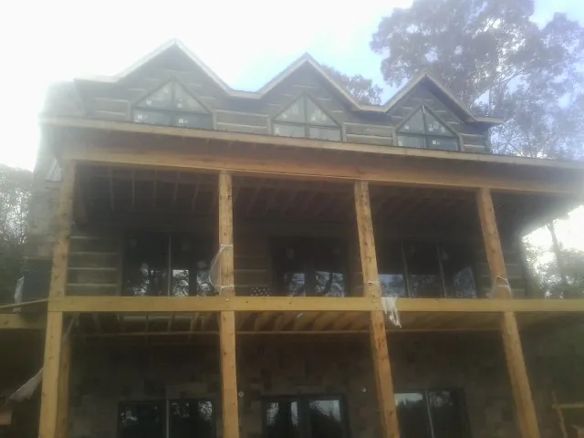 Dormers and porch framing on a large log home under construction — Roof Coating work by our crew in Powers