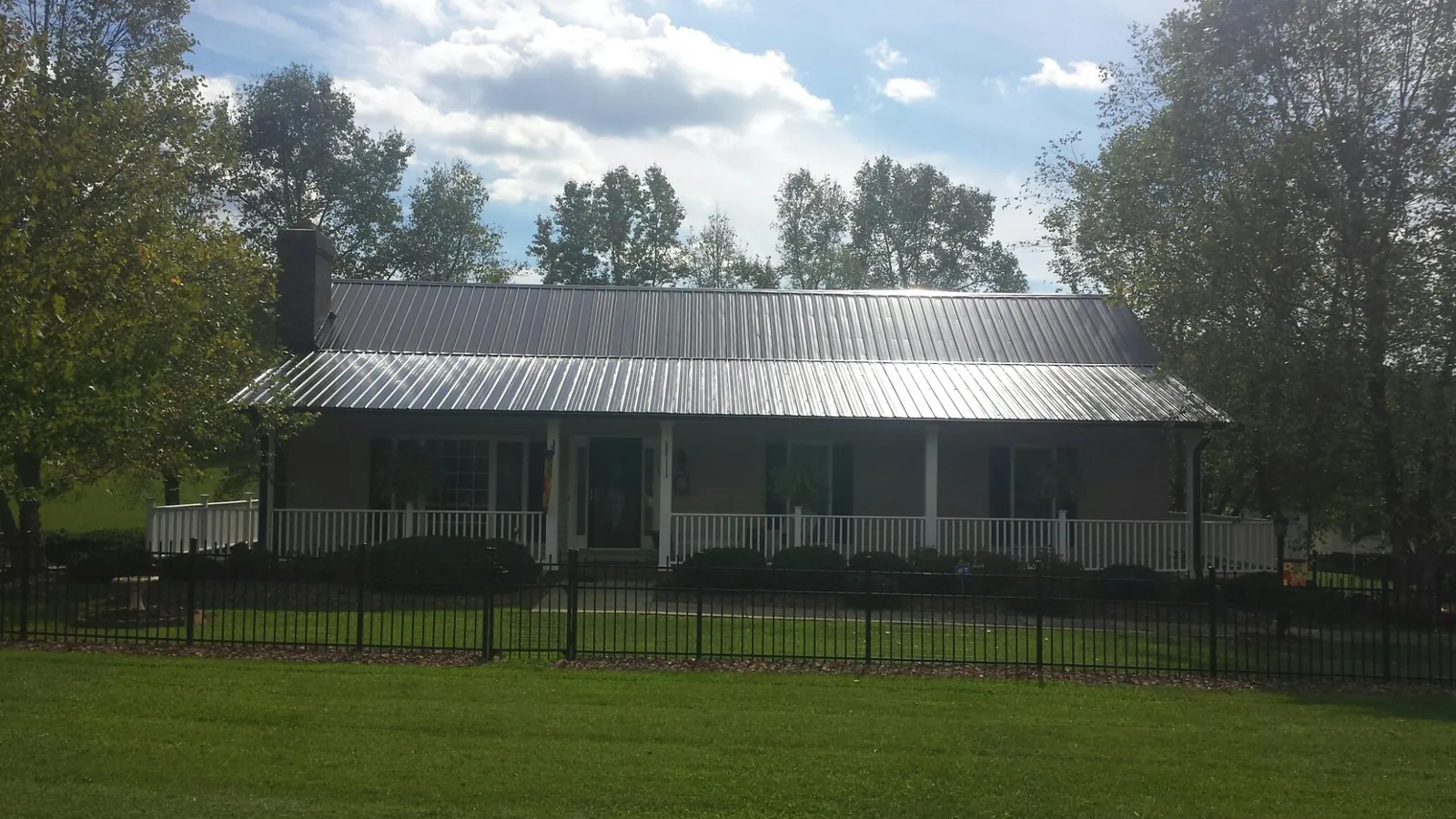 Gray metal roof on a brick ranch with a full width front porch — Gutter Guard Installation work by our crew in Powers