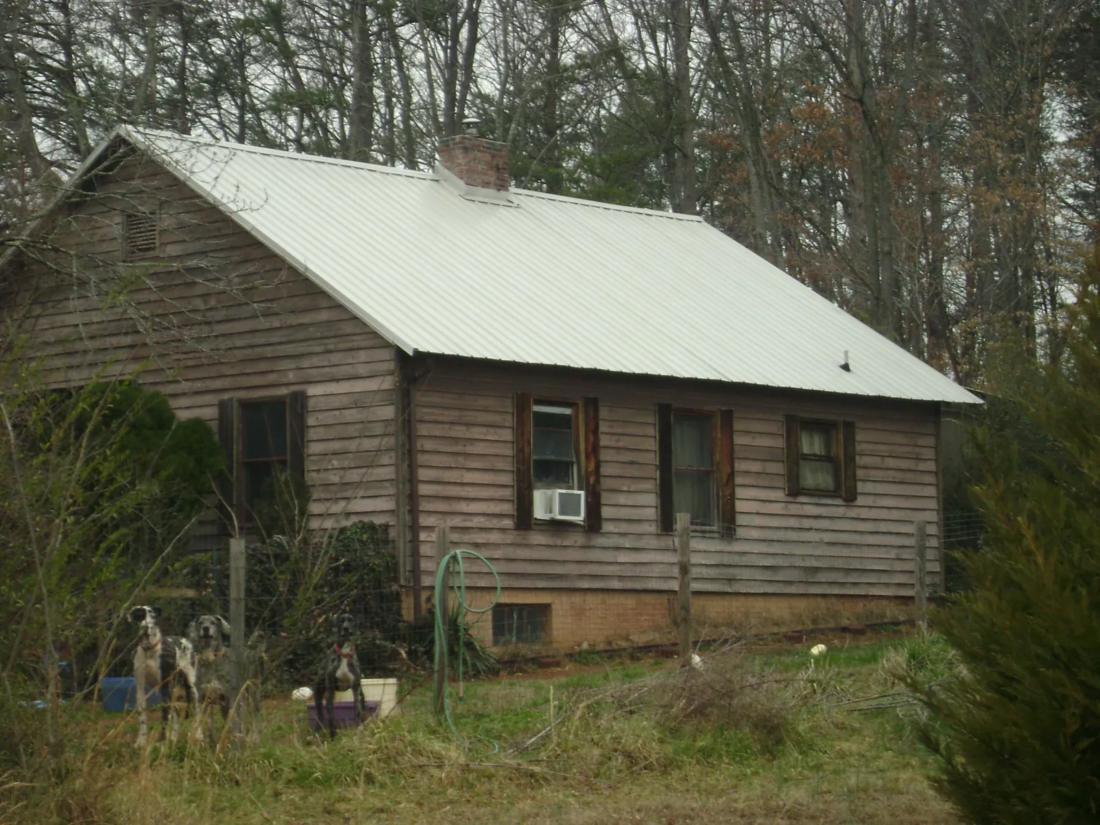 White metal roof on an old wood sided farmhouse, from a Metal Roof Installation job in Powers