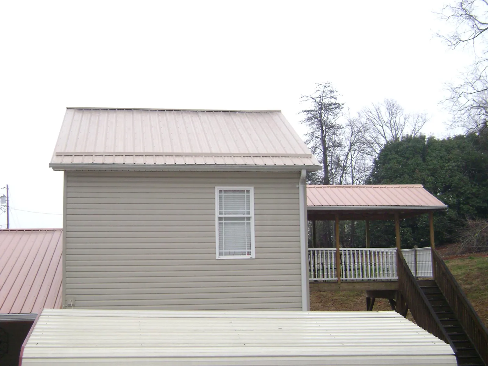 Tan metal roofs on a two story addition and attached porch, from a Roof Replacement job in Powers
