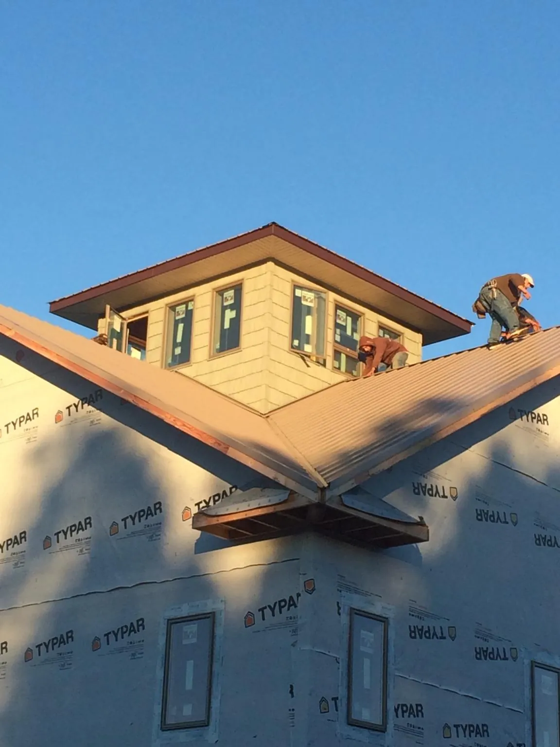Roofers working around a rooftop cupola on a new metal roof at sunset — Roof Waterproofing in Powers by Roofing Brothers